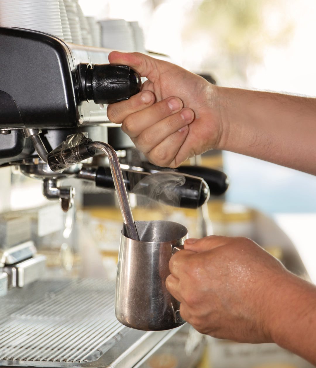 A barista steaming milk at an espresso machine